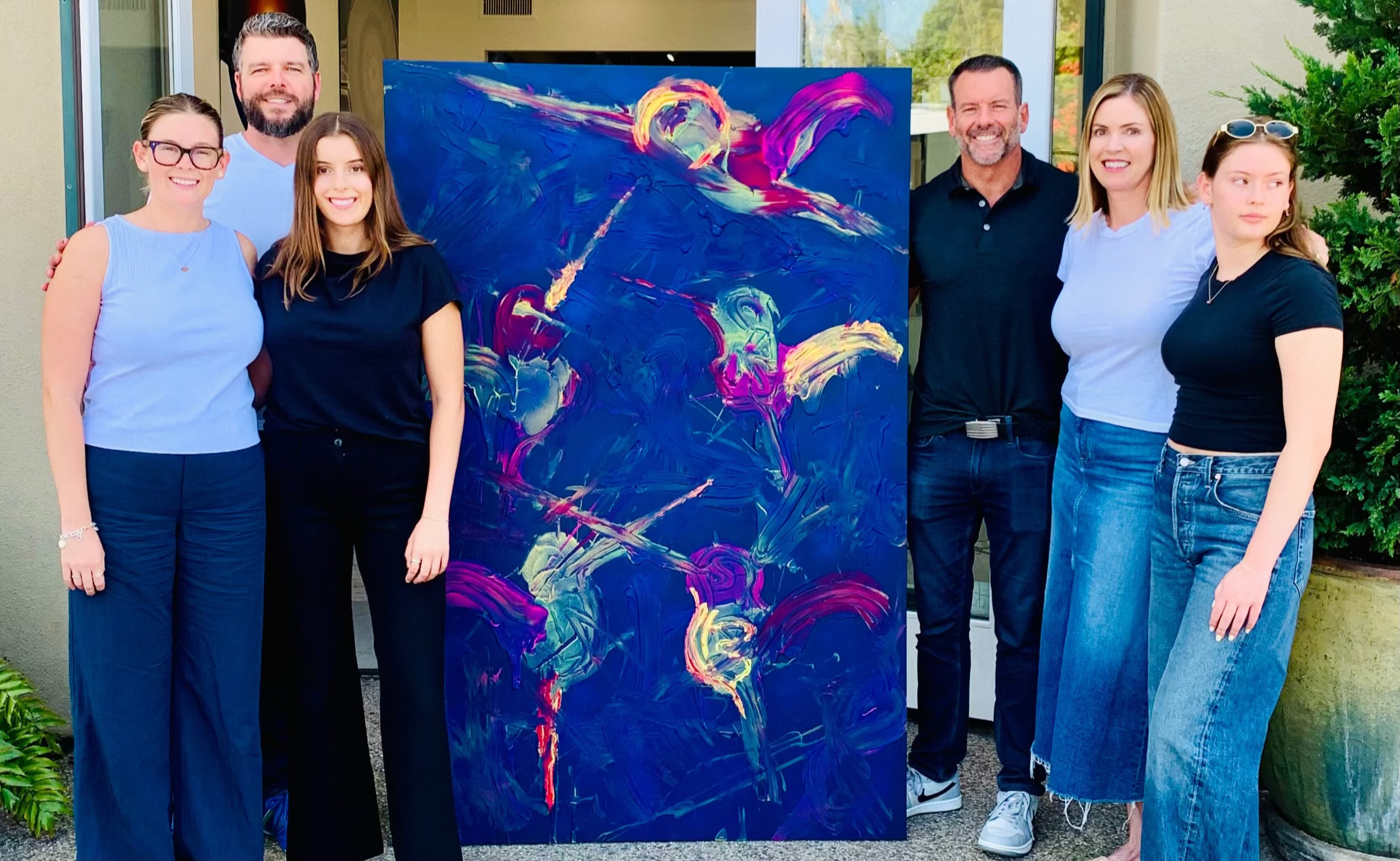 Group of people posing with a large abstract painting in front of a Ethan Blu Art Gallery