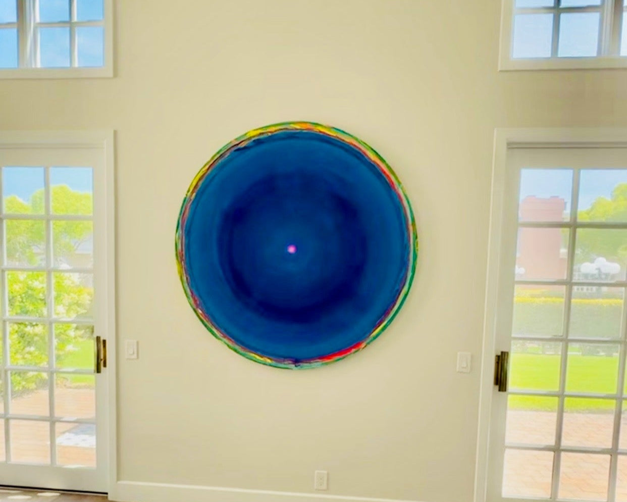 Colorful circular artwork on a wall in a room with large windows.