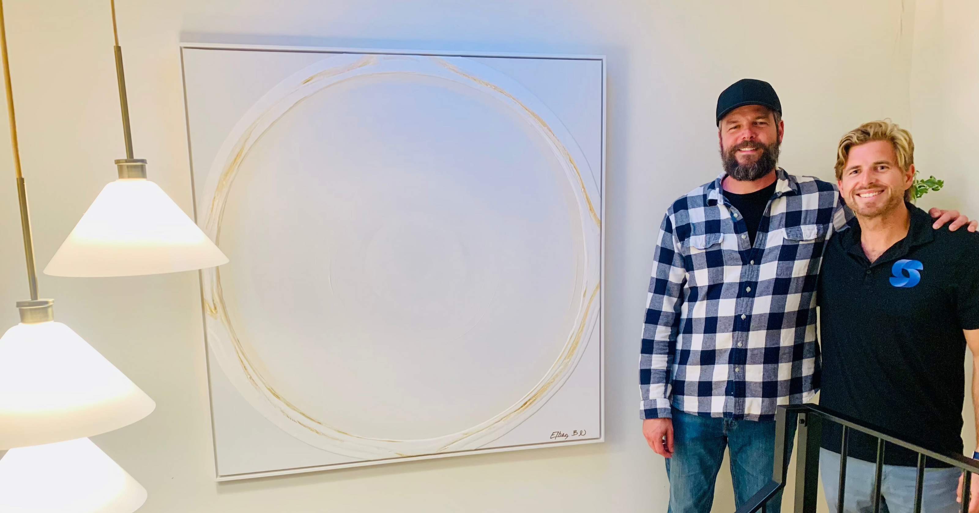 Two men standing on a staircase with a modern abstract Ethan Blu painting in the background