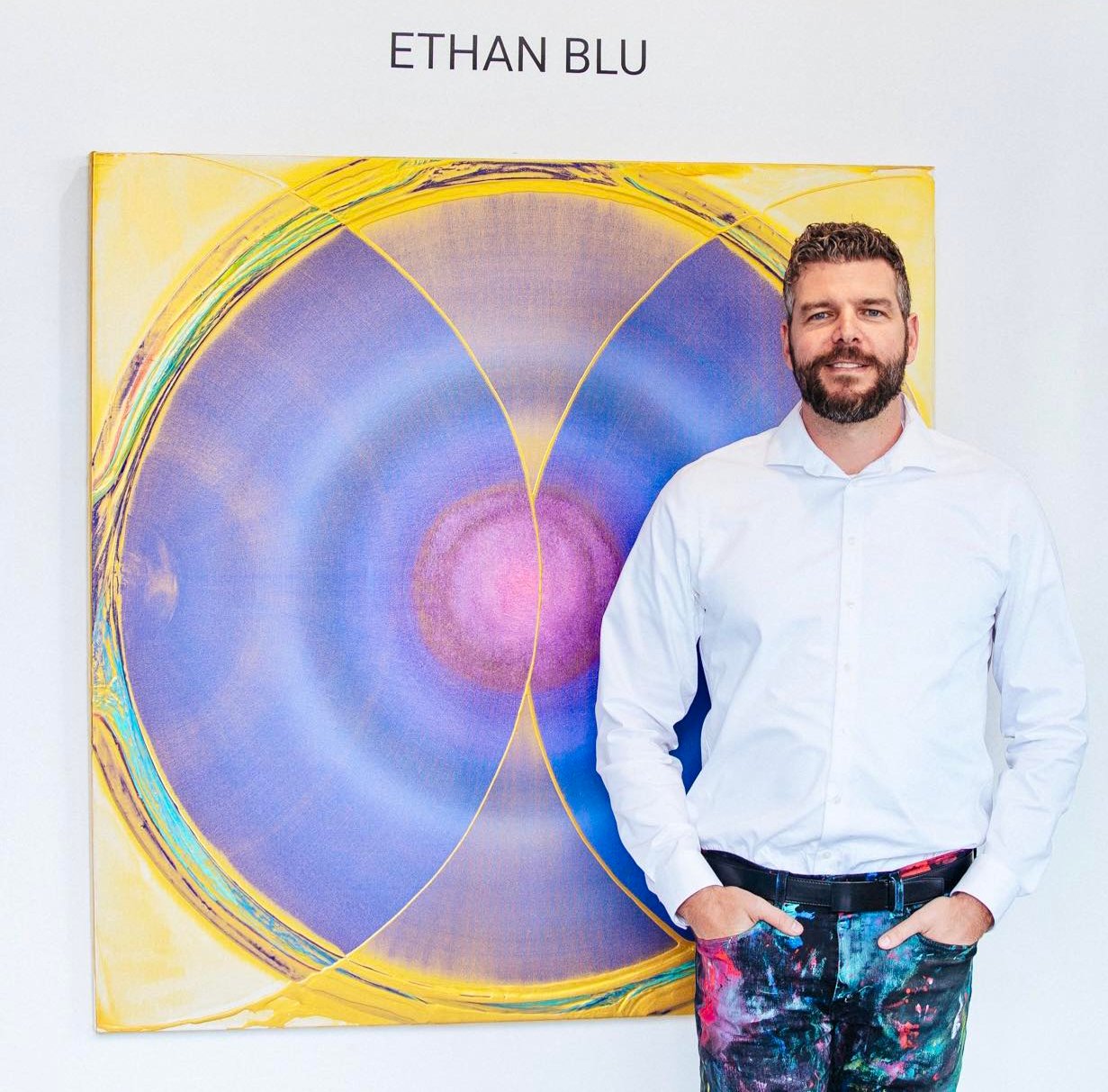 Ethan standing in front of a mindfulness circle painting in purple and gold